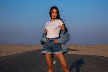 Attractive woman in white t-shirt on the road in the middle of the desert.