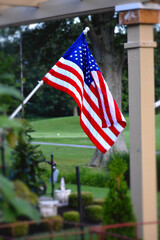American flag on flagpole in backyard. Fourth of July back yard decoration of America home. Memorial day. Patriotic backyard. Foreground blurred.