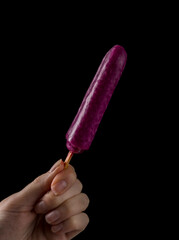 Female Hand Holding a Popsicle on black background. Grapes
