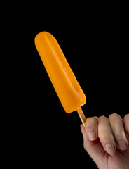 Female Hand Holding a Popsicle on black background. Cashew