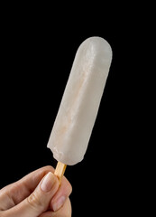 Female Hand Holding a Popsicle on black background. Lemon