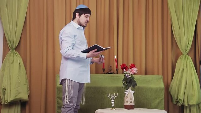 Before the chuppah ceremony, the Jewish groom reads prayers and psalms for siddur in the synagogue hall and makes kiddush for wine