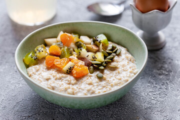 Bowl with oatmeal, tangerines and nuts, healthy breakfast 