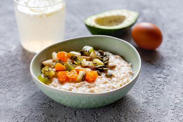 Breakfast with oatmeal, fruits, avocado and egg, close-up