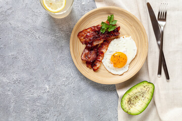 Keto breakfast with fried egg, bacon, avocado and lemonade, top view. Low carb concept