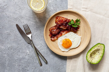 Breakfast with fried eggs, bacon and avocado, top view