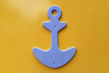 Wooden anchor on yellow background