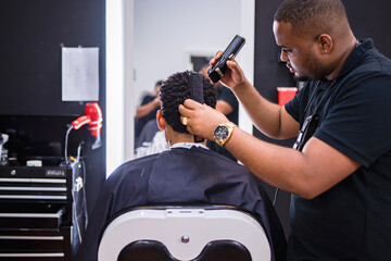 peluquero cortando el pelo a joven en barberia latina.con maquina de cortar el pelo cuidadosamente...