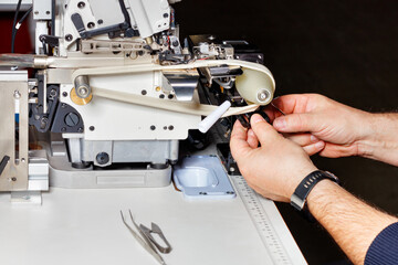 The master makes adjustments to a modern industrial electric sewing machine.