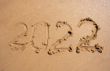 The numbers 2022 on the wet sand. The concept of the New Year 2022. Summer holidays and sea trips