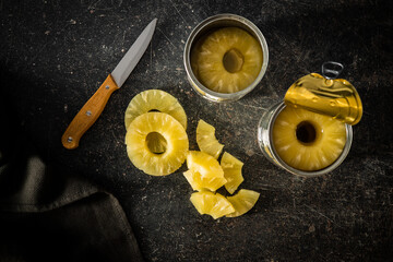 Canned sliced pineapple fruit on black table.