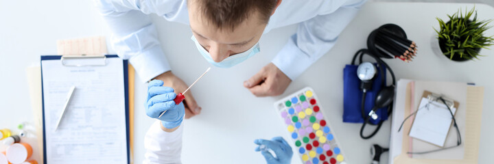 Nurse in medical mask taking swab from patients nose top view