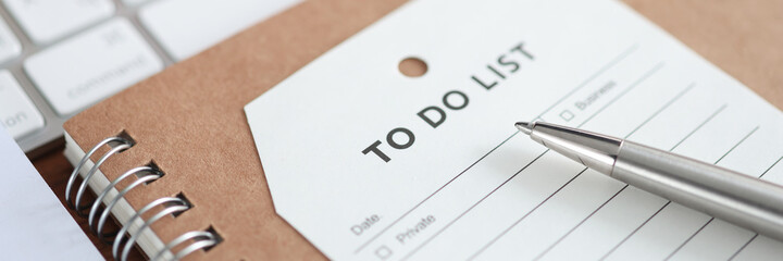 Paper with inscription to do list lying on notebook closeup