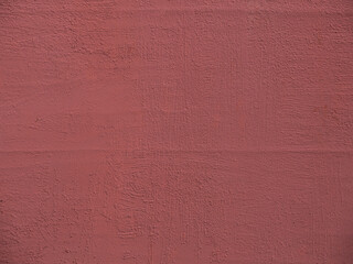 The texture of a dense burgundy paint on a cement covered plaster wall. Painted red metal background. The concept of a backdrop for design work.