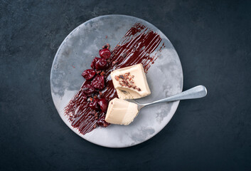 Modern style traditional blancmange almond pudding with cherry, chocolate cream and crumbles served...