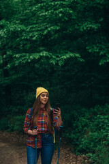 A hiker woman using smartphone for orientation while walking in the forest