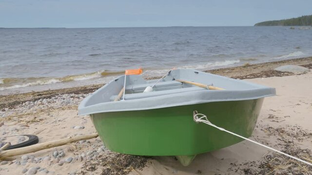 A green boat docked on the shore of the beach with the orange flaglet on it