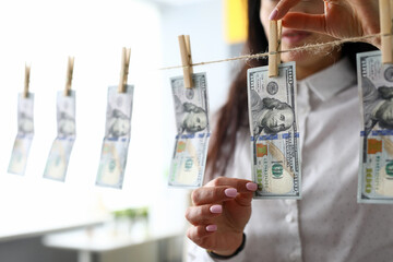 Female hands taking 100 dollar bill off clothes line