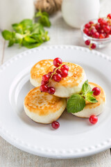 Cheesecakes with currant berries on a plate light background 