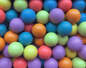 Fototapeta na wymiar Background from multicolored bright small wooden balls of blue, yellow, red, lilac and green colors. A beautiful summer bright background for your projects.