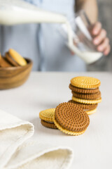 Cookies in the foreground in the background a girl pours milk into a glass 