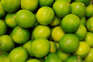 Pile of fresh green limes on market counter. Food background and lime harvest concept.