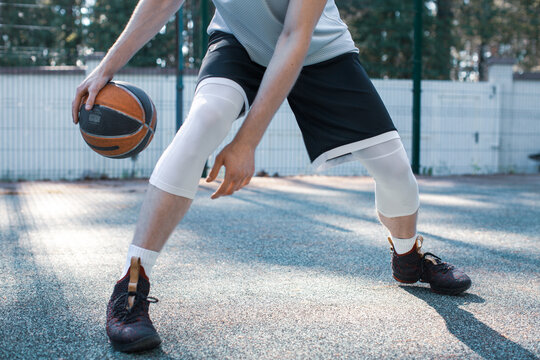 Professional american basketball player cool guy in action with ball dribbling on court outdoors, close up cropped photo