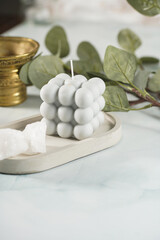 A grey-blue bubble candle on a concrete tray and white crystals on pastel blue background