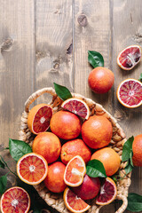Naklejka na ściany i meble Pile of blood oranges in a basket on a wooden table background. Flat lay, top view, copy space