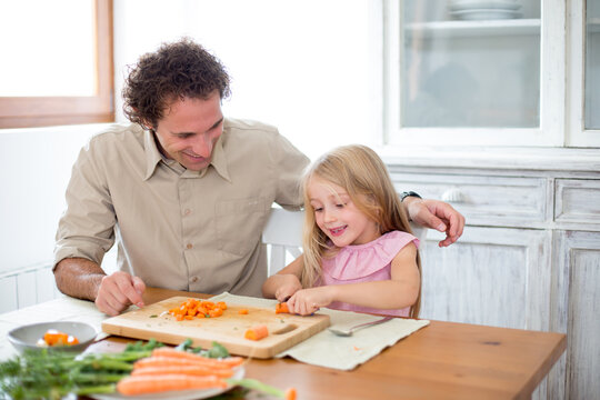Family preparing a healthy meal in the kitchen at mediterranean home.
