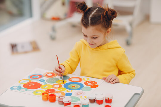 Little girl painting art picture indoor kindergarten. Home table with brush and watercolor paints