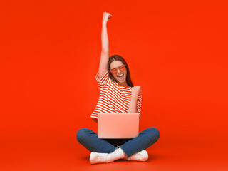 She is a winner! Excited young female with laptop isolated on red background