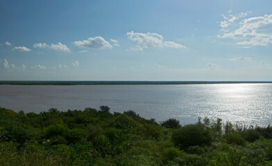 Aerial view of the green tropical jungle and river at sunrise. The bright sun reflection in the surface of the water.