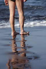 in the photo there are only feet and traces of these feet on the fine black sand on the shores of...