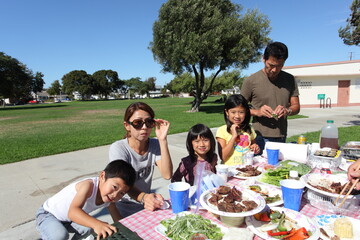 Two families enjoying BBQ in the park