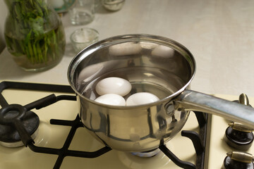 White chicken eggs are boiled in a ladle with wate