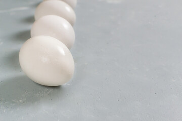 Five white chicken eggs lie on a gray background.