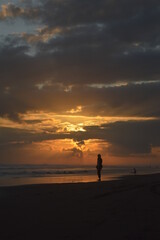 a person walking on the beach at sunset