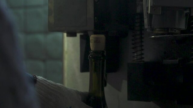 Sealing of champagne with a stopper at a factory of sparkling wines. Wire braiding the neck of a bottle with champagne. Production of champagne. Bottle of champagne at factory.
