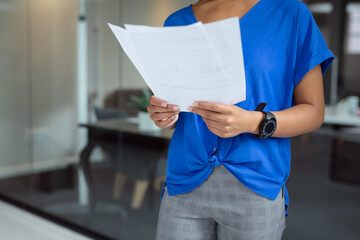 Midsection of african american businesswoman looking at paperwork standing in office