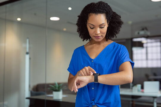 African american businesswoman checking smartwatch standing in office