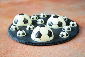 A delicious dessert of chocolate football balls of different shapes on a black serving plate - a concept of sports photography for a football fan