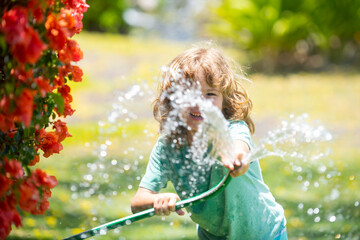 Kids play with water garden hose in yard. Outdoor children summer fun. Little boy playing with...