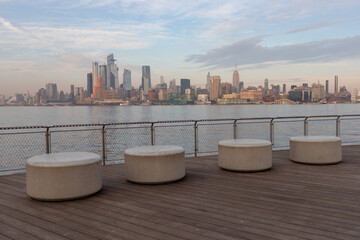 Stone Seats at a Park along the Hoboken New Jersey Riverfront with the Manhattan New York City Skyline in the Background - obrazy, fototapety, plakaty