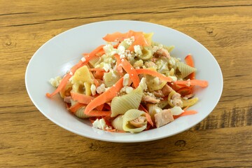Cold salmon pasta dish with carrots and feta cheese and Greek feta cheese salad dressing on white bowl