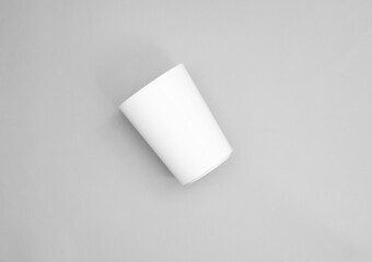 a cup in oblique position from top point of view. minimal shot for simple mockup. white plastic cup on grey background. realistic mockup for promotion.