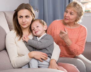 Two women are quarreling for upbringing toddler at home.