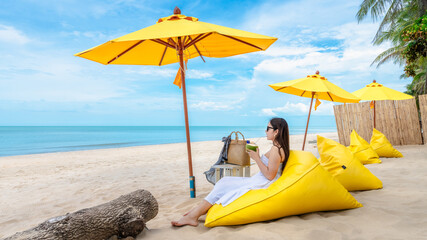 Summer lifestyle traveler woman relaxing on bean bag beach chair in front of vacation exotic beach,...