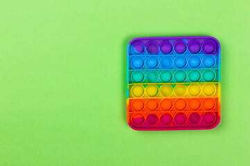 Pop it fidget toy. Fashionable anti-stress gift on a green background. LGBT flag and rainbow colors. A bright thing for children and adults made of silicone