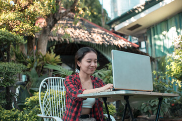 A motivated teenage girl busily types on the laptop for his her thesis on a table by the garden...
